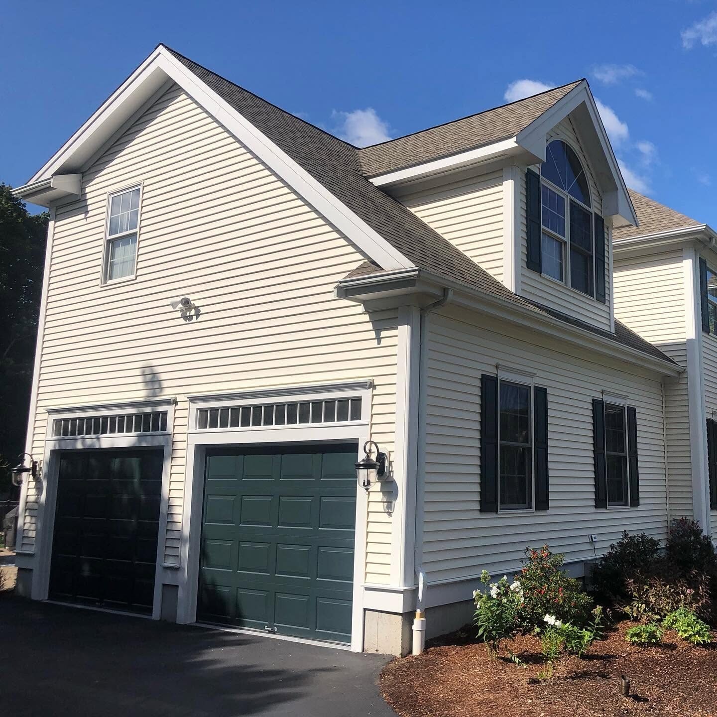 Cream siding with deep green garage doors and shutters