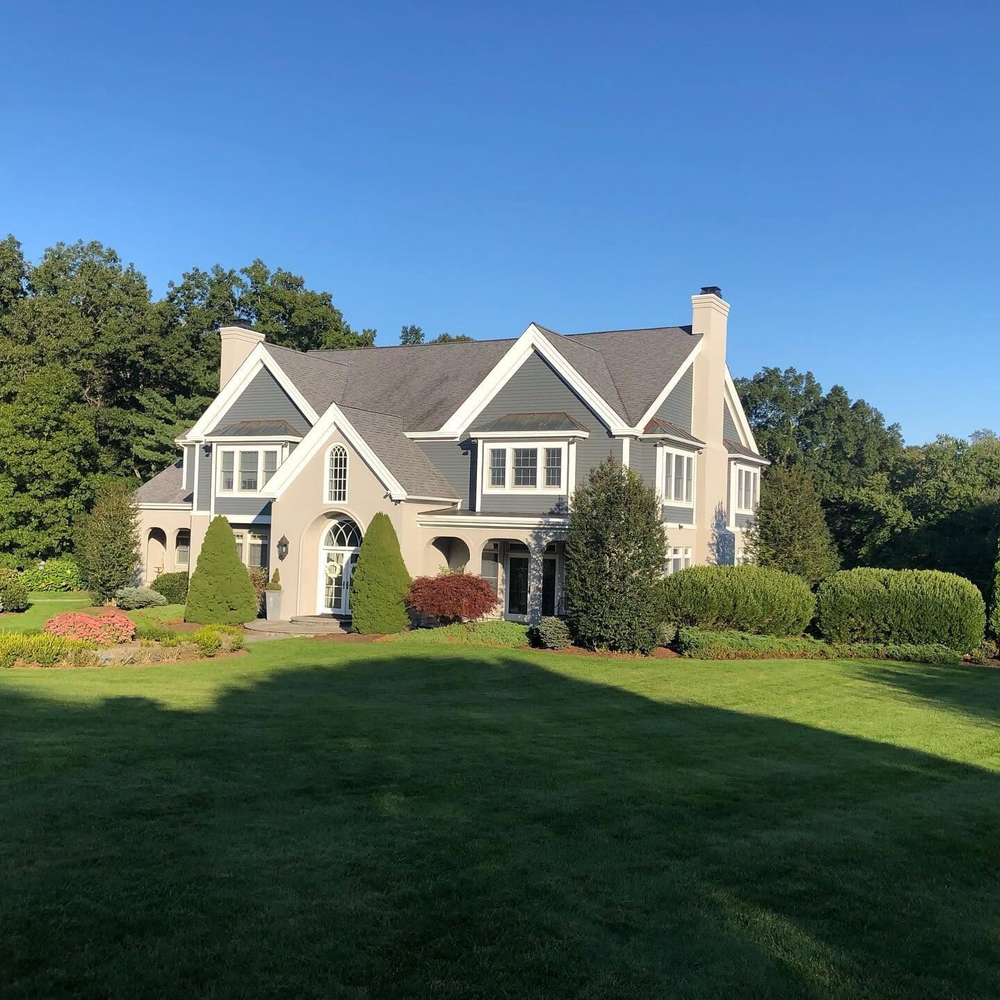 Large colonial home exterior repainted with black shutters