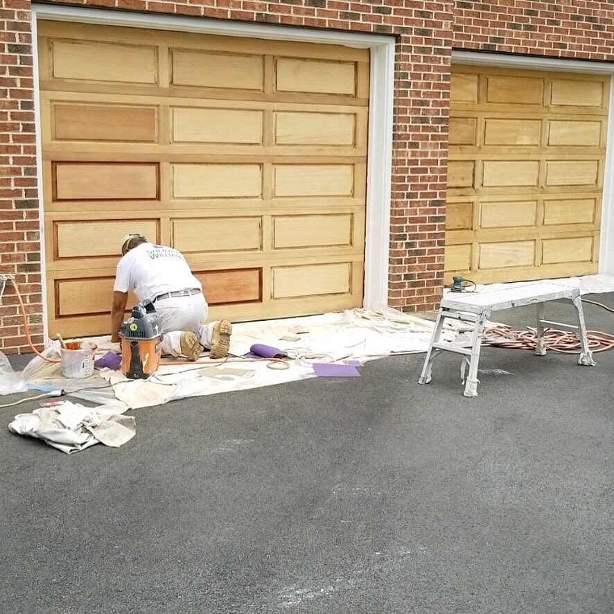 Painter staining wood garage doors