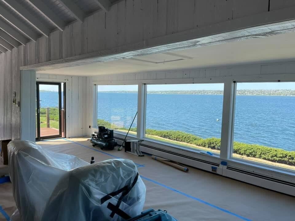 Waterfront living room with furniture covered and floors protected for a repaint